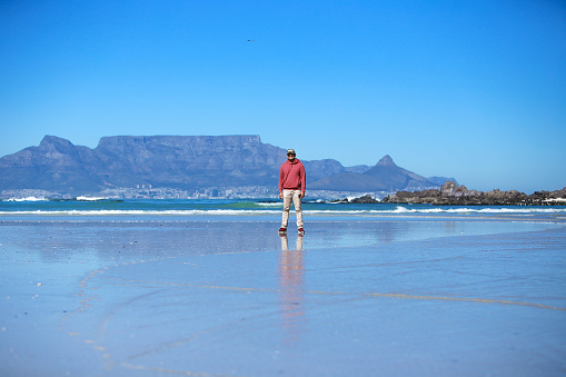 South Africa, Cape Town, man standing on the beach with table mountain behind