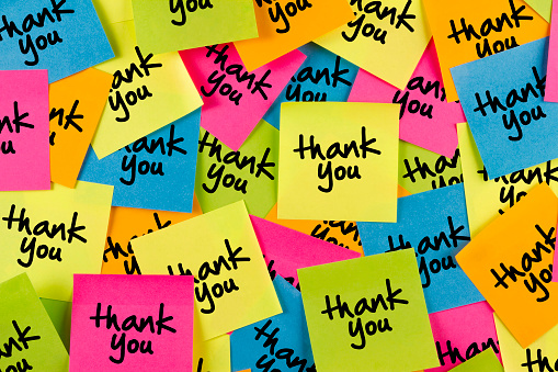 Thank you sticky note with multiple colored adhesive notes on bulletin board