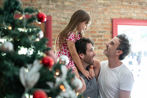 Lovely argentina gay family decorating the christmas tree at home
