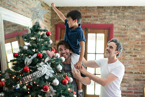 Lovely argentina gay family decorating the christmas tree at home