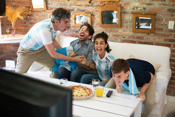 aficionados argentinos al fútbol alegres, gritando comiendo pizza para llevar y mirando juego de fútbol - argentina mundial fotografías e imágenes de stock