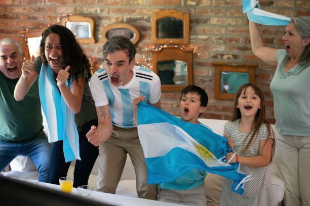 aficionados de fútbol familiar argentinos alegres, gritando comiendo pizza para llevar y mirando juego de fútbol - argentina mundial fotografías e imágenes de stock