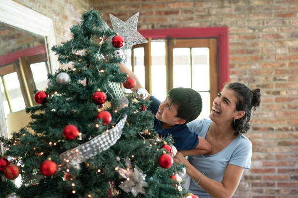 istock Single mother and son decorating the christmas tree at home 1196680087