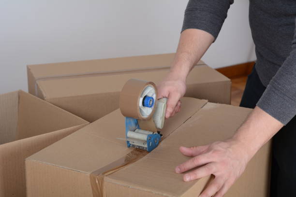 istock Man sealing a shipping cardboard box 1196680234