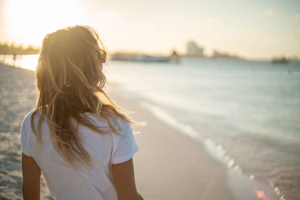 istock Woman relaxing on beach at sunset 1196680275