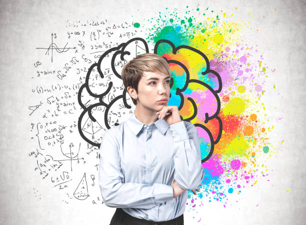 Young woman, analytical and creative thinking Thoughtful young blonde businesswoman standing near concrete wall with colorful brain sketch with formula drawn on it. Concept of analytical and creative thinking drawing of a advanced math formulas stock pictures, royalty-free photos & images