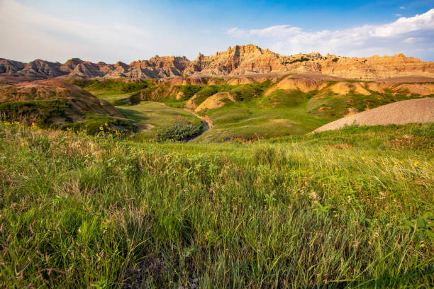 Rugged terrain in the Badlands National Park Rugged dirt and rock hills rise over a green grassed valley in the Badlands National Park in South Dakota. south dakota stock pictures, royalty-free photos & images