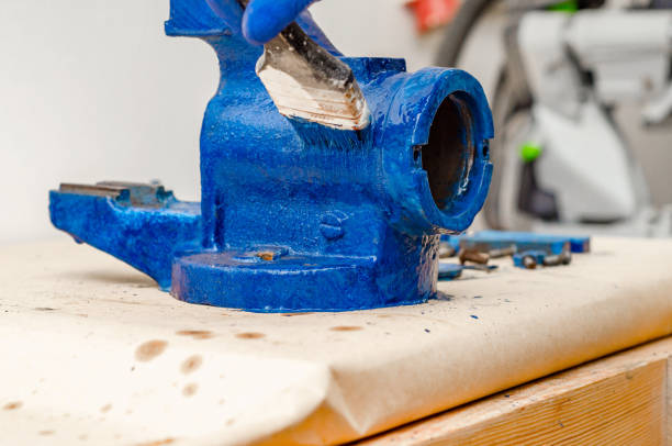 istock Worker paints a metal vise with blue paint. Stripping old paint 1196693874