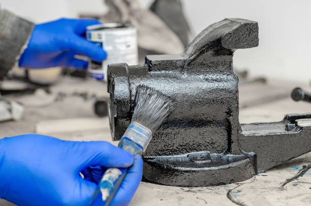 hand in blue rubber gloves paints metal parts of an old vise with black paint with a brush - brushing human hand paintbrush artist imagens e fotografias de stock