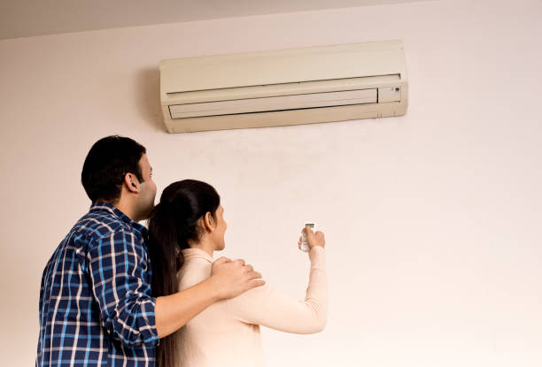 istock Couple adjusting the temperature of air conditioner using remote control 1196697373
