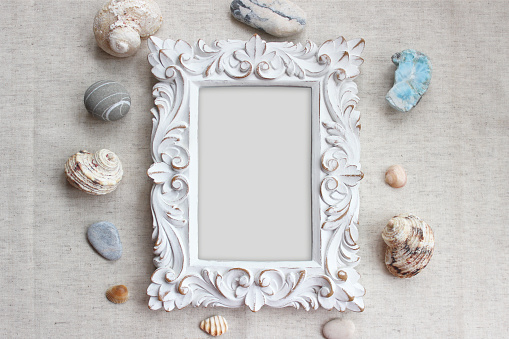 Vintage picture frame surrounded by sea shells and stones. Mock-up in boho style.