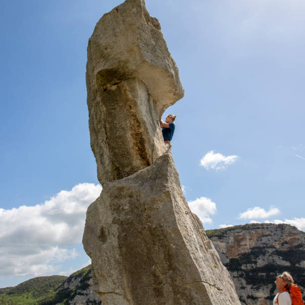 deux hommes grimpent le pinacle raide de roche au-dessus de la vallée - 16017 photos et images de collection