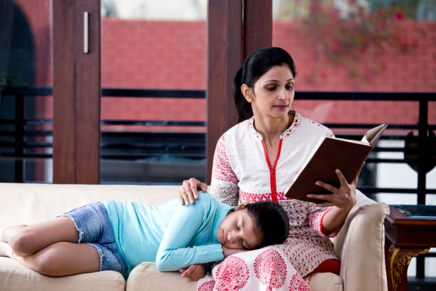 istock Woman reading book while daughter is sleeping on her lap 1196703574