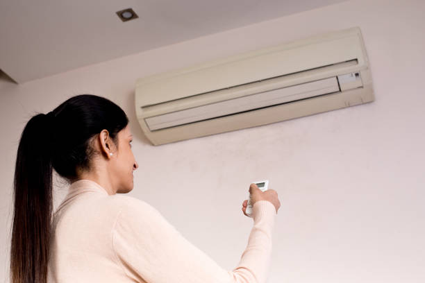 istock Woman adjusting the temperature of air conditioner using remote control 1196704419