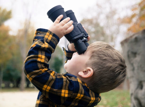 istock Little boy with binoculars exploring forest in autumn 1196705382