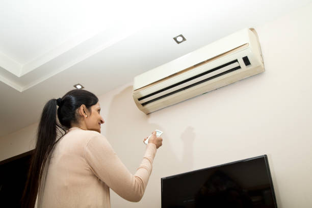istock Woman adjusting the temperature of air conditioner using remote control 1196706659