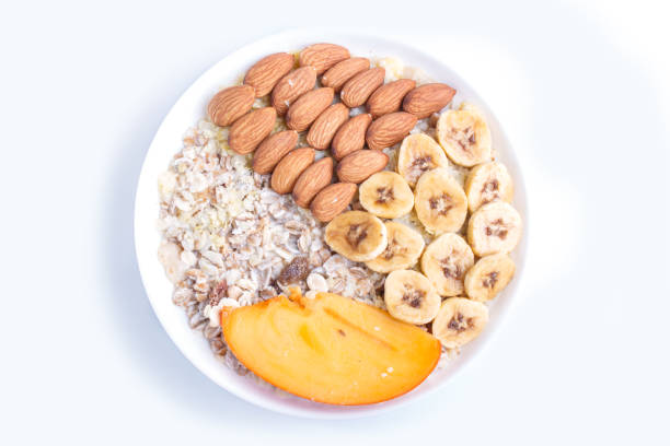 istock A plate with muesli, almonds, banana, persimmon isolated on white background. top view. 1196707985