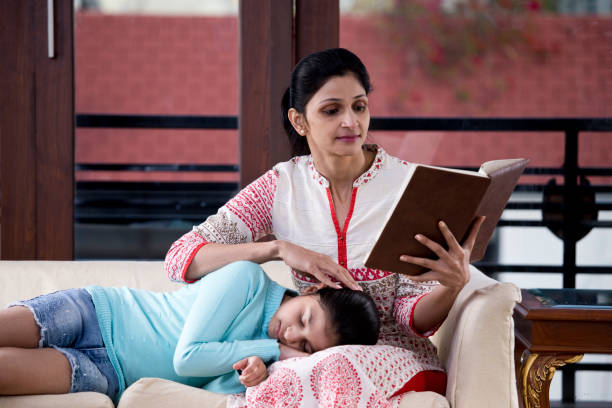 istock Woman reading book while daughter is sleeping on her lap 1196708985