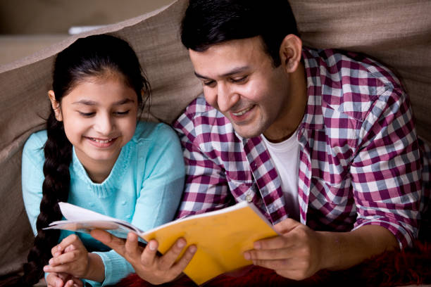 istock Father reading a book to his daughter under cover 1196709776