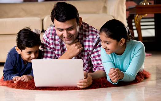 Father and children using laptop in the living room at home