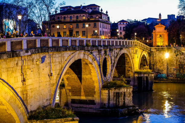 Rome, Italy, December 26 -- The sunset light warms the Tiber river in Rome along the imposing travertine embankments built at the beginning of the twentieth century, with a view of the famous Ponte Sisto and a view of Trastevere. Image in HD format