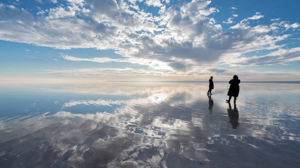 istock Young couple walking on salt lake at sunset 1196711752