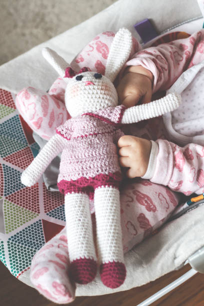 istock Baby's hands holding funny knitted rabbit toy 1196712465