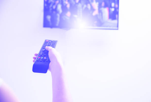 istock Woman is holding the remote control in her hands. Using TV at home. 1196714140