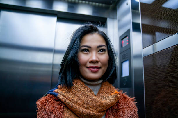 Asian woman checking herself out in elevator mirror