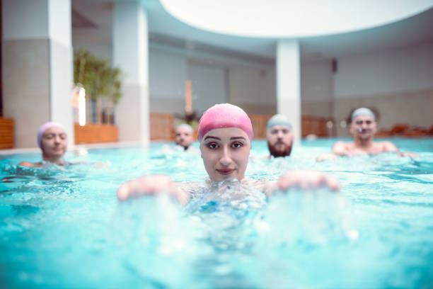 mujer y sus amigos trabajando en sus habilidades de natación en la piscina - sports venue luxury love enjoyment fotografías e imágenes de stock