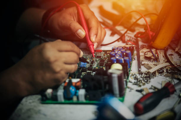 istock Technician engineer in workshop. Repairman is checking circuit board of electronic device on the table 1196718461