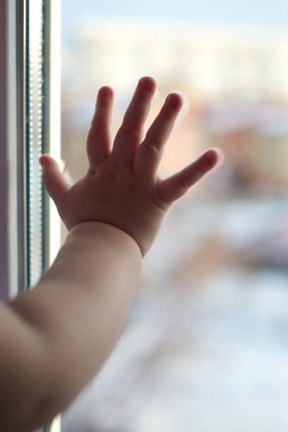 istock A small child touches a window with his fingers 1196719473