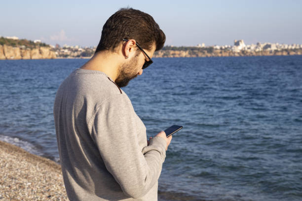 istock Portrait of a handsome young man using a smartphone at the beach 1196725726