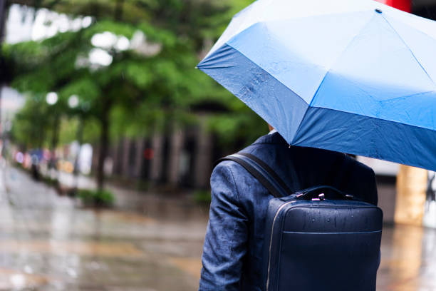 Rear view of an unrecognizable businessman walking down the city streets on his way to the office while it's raining outside.