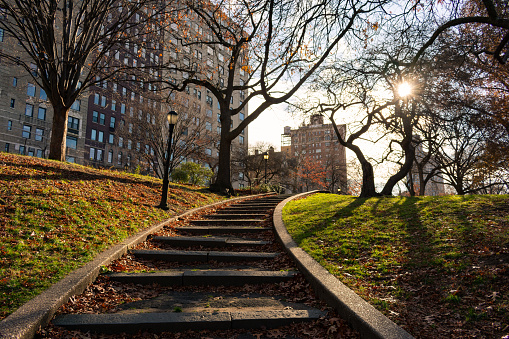Curving steps at Riverside Park on the Upper West Side of New York City with old skyscrapers and a shining sun