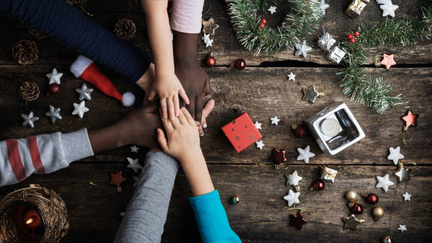 Family of mixed races stacking their hands in Christmas setting stock photo