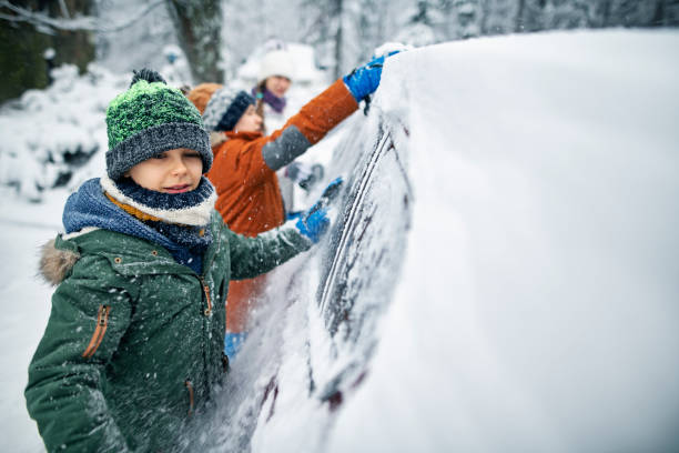 niños retirando la nieve del coche después de la ventisca - thick snow fotografías e imágenes de stock