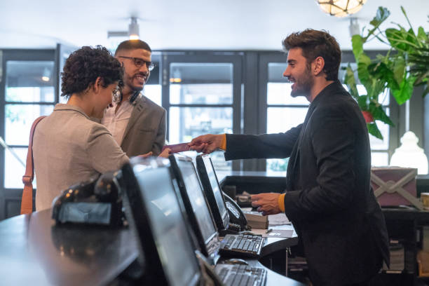 Young business couple checking in at hotel and receptionist man helping them.