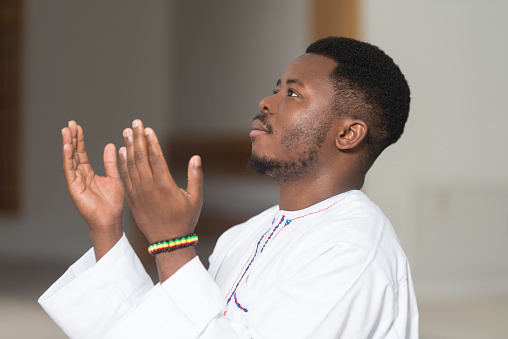 African Muslim Man Making Traditional Prayer To God While Wearing A Traditional Cap Dishdasha