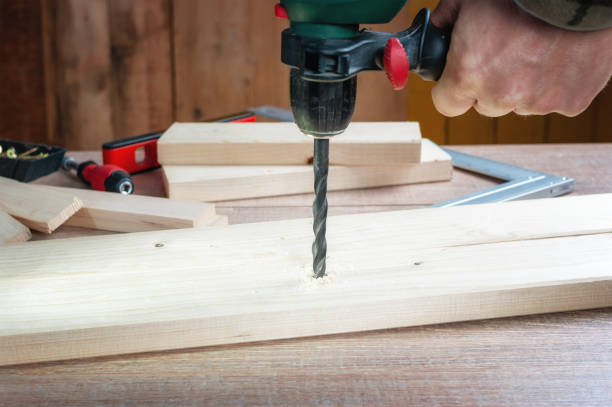 istock Man making hole into the wood with drill 1196735383