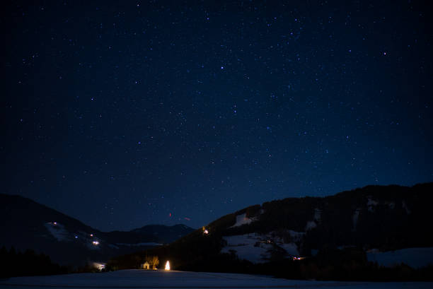 lonely chapel with illuminated Christmas tree under a wintry starry sky