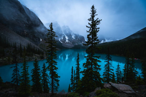 Moraine Lake in Banff Canada in the morning with fog and deep blue colors.
