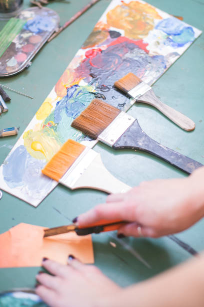 istock artist cutting paper on table with brushes and paint 1196742092