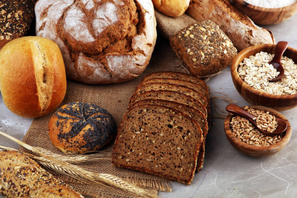 istock Assortment of baked bread and bread rolls and cutted bread on table background 1196743064