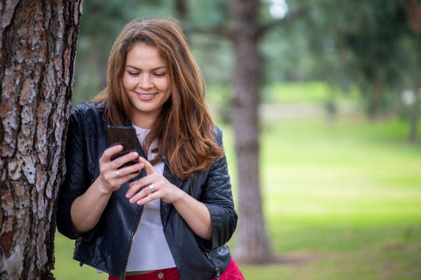 istock Russian Woman using smartphone in a park 1196744745