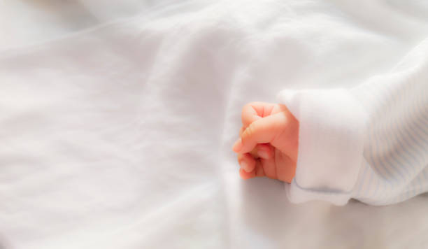 ソフトフォーカスによる白い生地のパターンに赤ちゃんの手