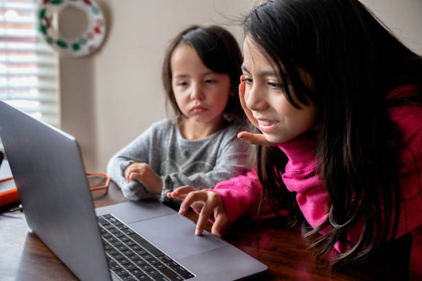 istock Two Sisters, nine years and three years old working together on a laptop computer 1196751909
