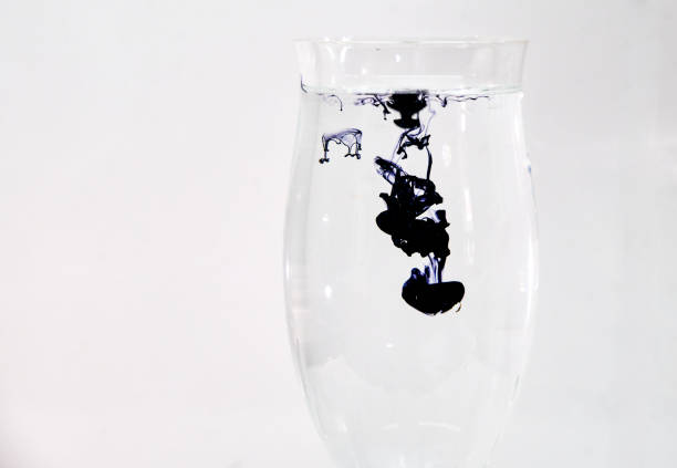 istock Blue and black ink dropping into a wine glass 1196752951
