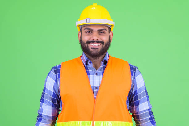 istock Happy young overweight bearded Indian man construction worker smiling 1196752989