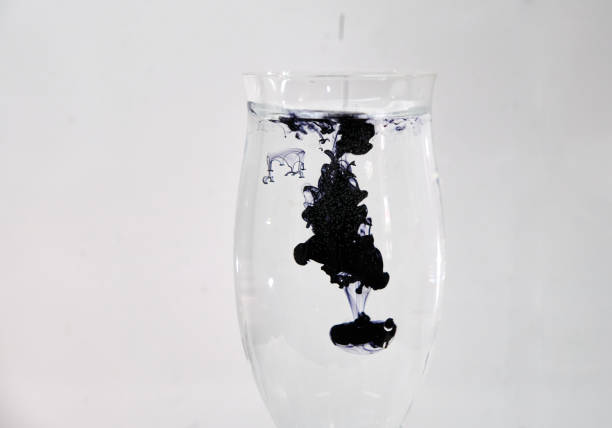 istock Blue and black ink dropping into a wine glass 1196753017